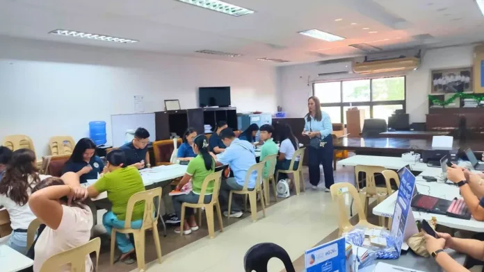Department of Foreign Affairs staff and residents of the 1st District of Misamis Oriental process passport applications during the Passport on Wheels mobile outreach service held in Lagonglong and Talisayan.