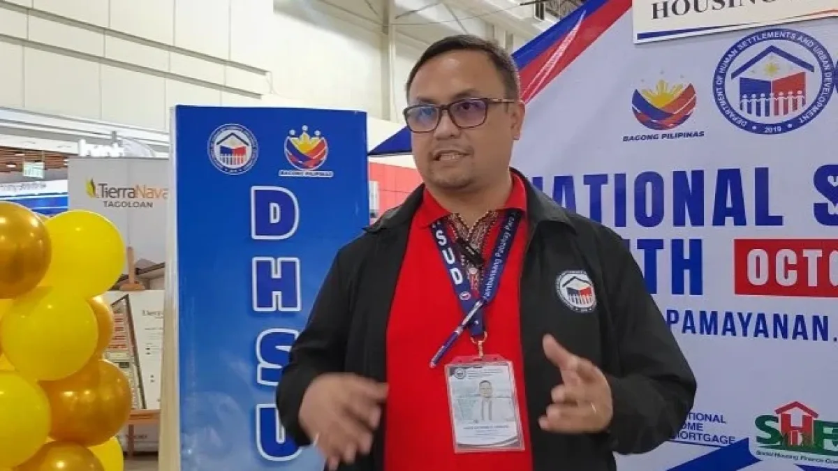 DHSUD-10 Regional Director Paris Raymond Gaballo speaks with a colleague near a National Shelter Month banner during a workshop on homeowners' association financial literacy.