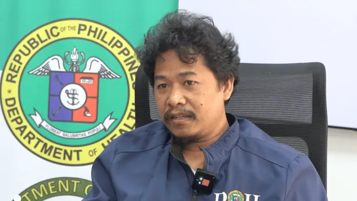 Department of Health Northern Mindanao Development Management Officer Reymar T. Joromo sits in front of a DOH seal during a briefing on the MAIFIP medical assistance program.