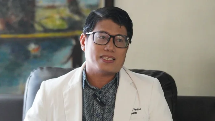 Dr. Abel Santini G. Permites, an RITM-DOH certified trainer on rabies and animal bite management, wearing a white medical coat and glasses while speaking during an interview in Cagayan de Oro City.