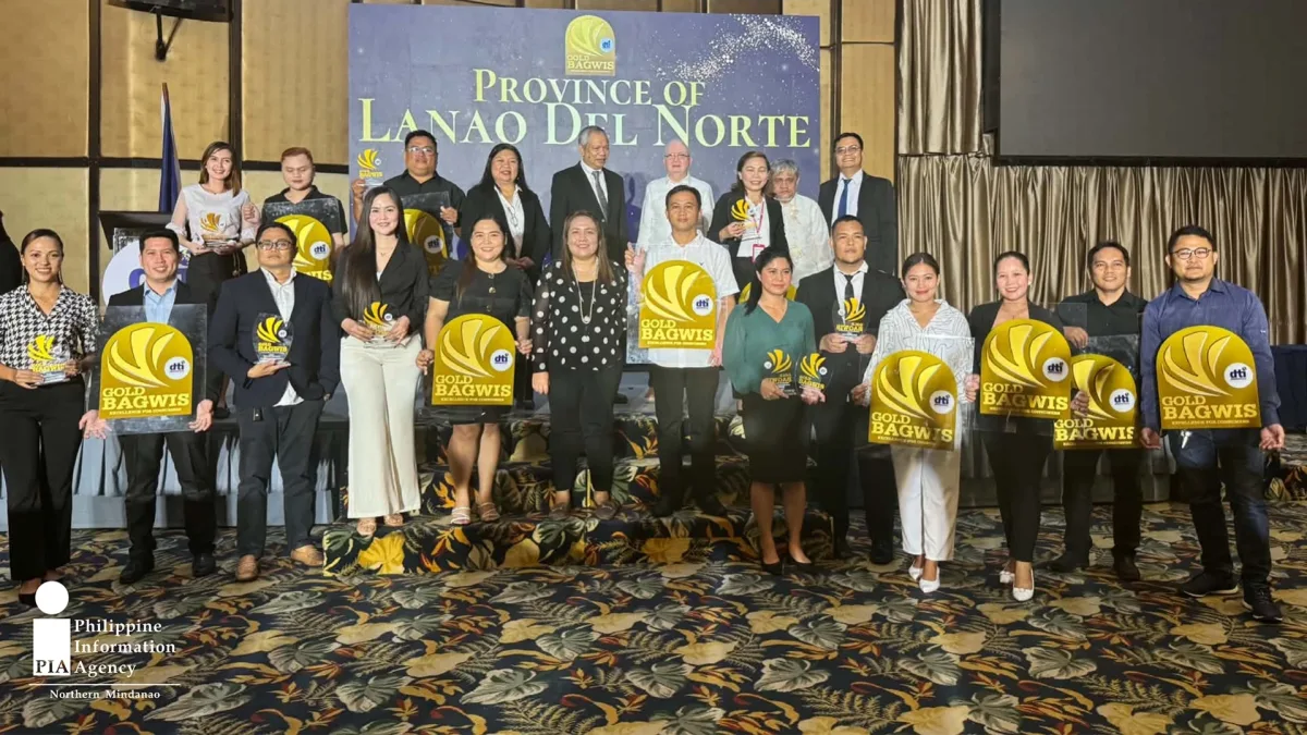 Business owners and store representatives from Lanao del Norte pose on stage holding gold DTI Bagwis Award plaques during the Consumer Welfare Month 2026 recognition ceremony in Cagayan de Oro City.