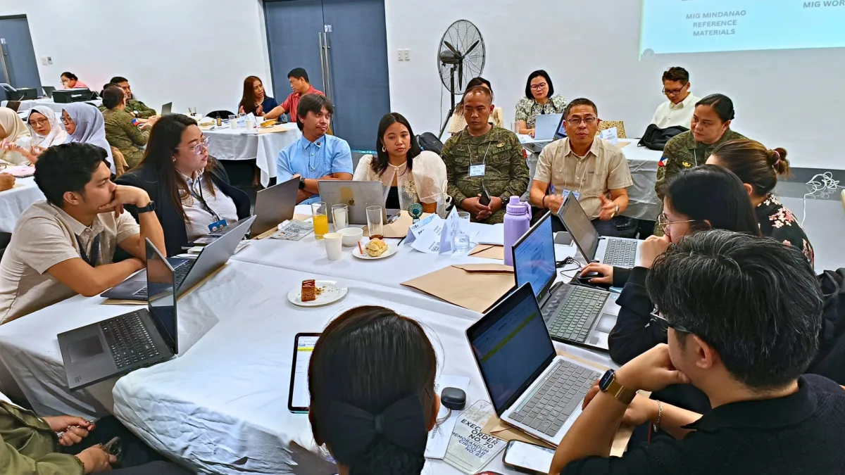 Government communicators, military officers, and public information personnel collaborate around a table with laptops during an ELCAC communications strategy workshop in Cagayan de Oro City.