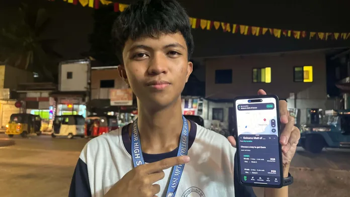 Seventeen-year-old Grade 12 student Francisco Navalta, wearing an Assumption College of Davao lanyard, holds up his smartphone displaying the interface of his DavaoGo transit navigation application.