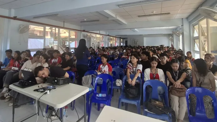 tudents at Gingoog City United College listening to a health education session on STI, HIV, and AIDS awareness during a food handlers training seminar inside a classroom setup.
