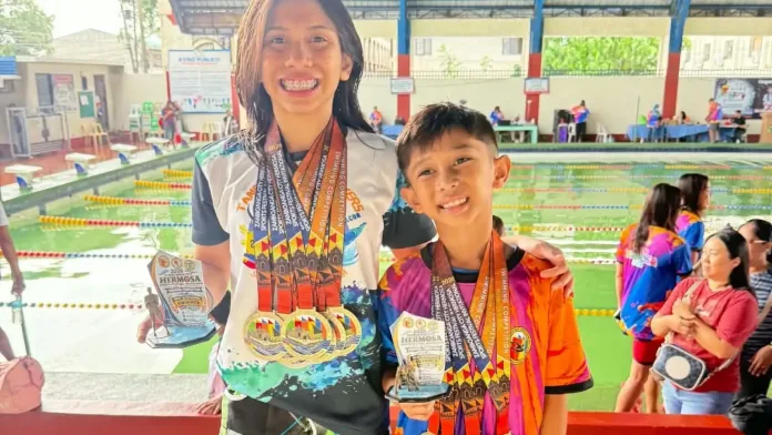 Cousins and Tangub City swimmers Hera Raagas Suerte (13) and Reign Raagas Sumaban (7) smile while displaying their Most Outstanding Swimmer trophies and medals at the Joaquin F. Enriquez Memorial Sports Complex in Zamboanga City.