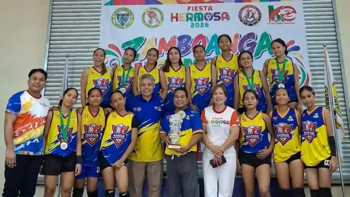 Members of the Hardam Furigay Colleges Foundation, Inc. (HFCFI) Lady Fury Spikers pose on stage with their championship trophy and medals after winning the women's division at the Zamboanga Hermosa Volleyball Tournament 2026.