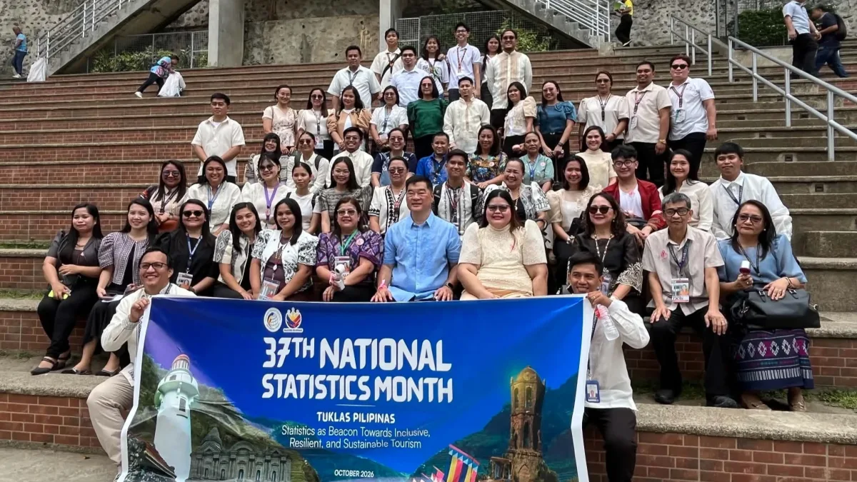 City officials, PSA representatives, and event delegates display the 37th National Statistics Month banner while sitting on outdoor stone steps in Iligan City.