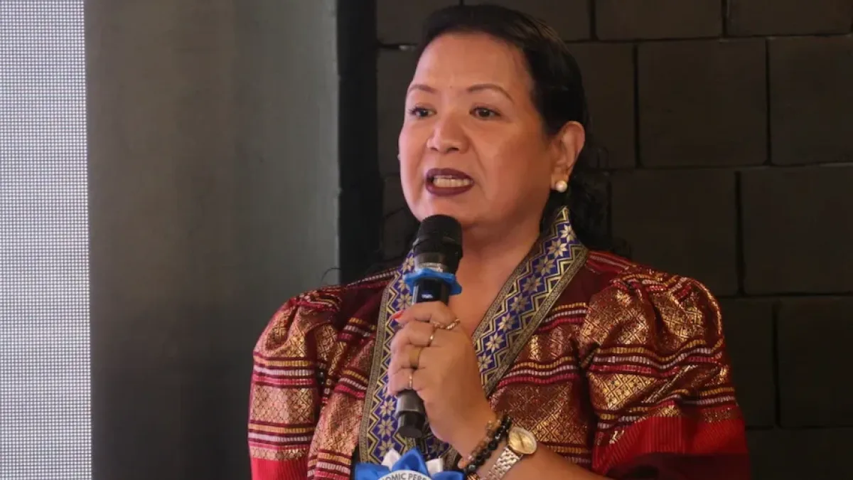 Philippine Statistics Authority-Misamis Occidental Chief Statistical Specialist Julieta M. Nacario speaks into a microphone while wearing traditional patterned attire during the 2025 Provincial Product Accounts economic dissemination forum in Ozamiz City.