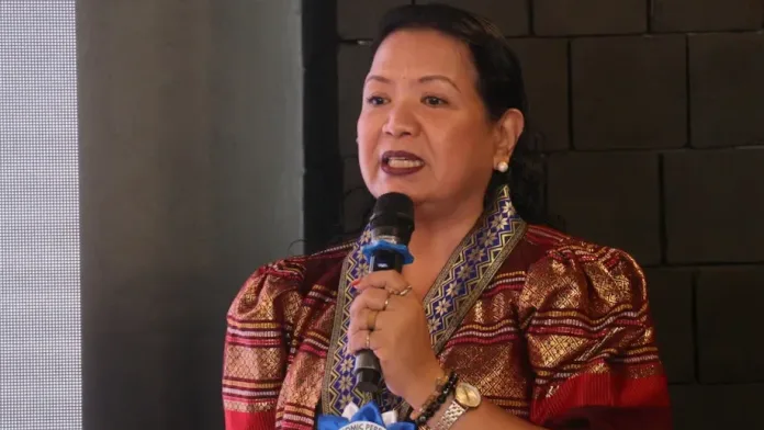 Philippine Statistics Authority-Misamis Occidental Chief Statistical Specialist Julieta M. Nacario speaks into a microphone while wearing traditional patterned attire during the 2025 Provincial Product Accounts economic dissemination forum in Ozamiz City.