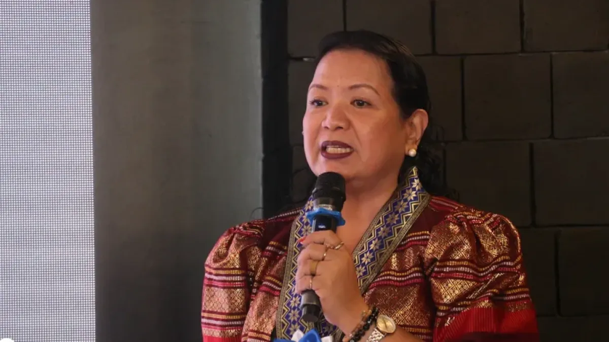 Philippine Statistics Authority-Misamis Occidental Chief Statistical Specialist Julieta M. Nacario speaks into a microphone while wearing traditional patterned attire and an official event pin during an economic dissemination forum.