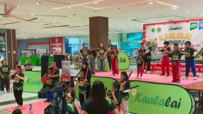 Children with special needs perform adaptive self-defense drills holding practice staffs on a stage inside CityMall Cotabato during the Kaalalai Project showcase.