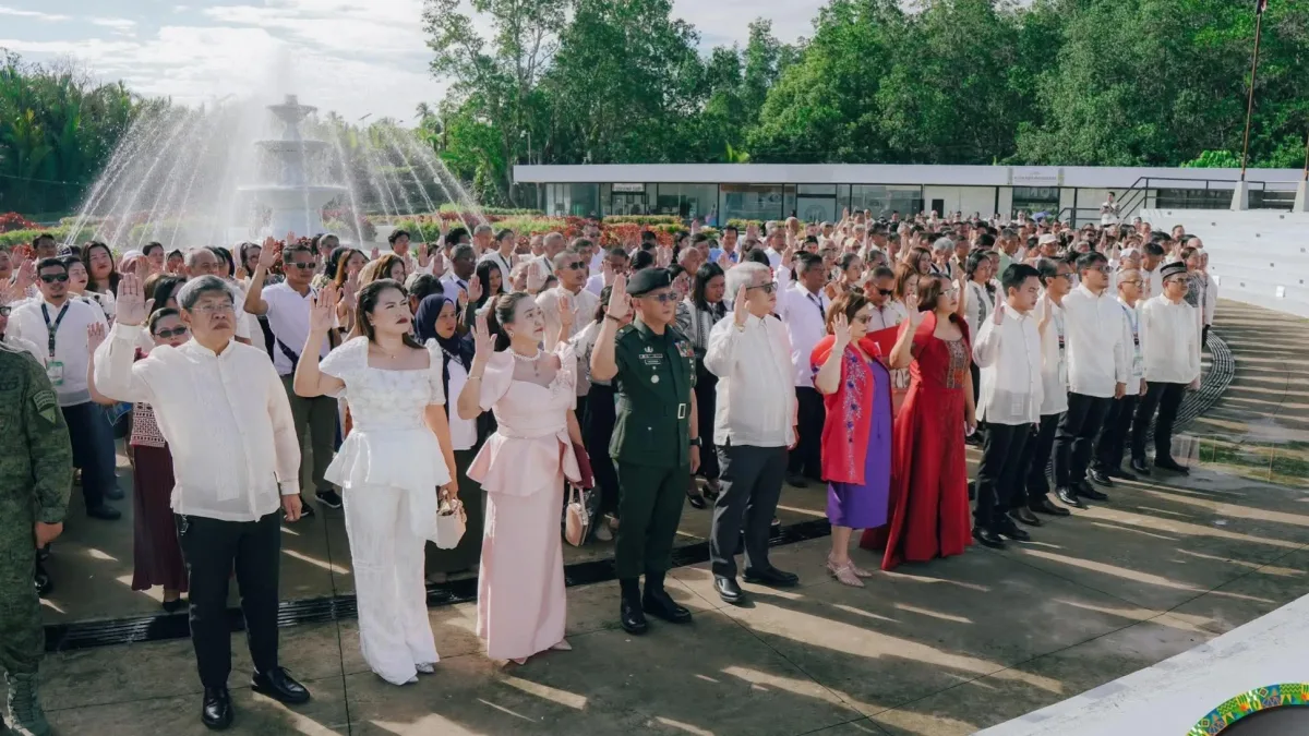 Local officials, municipal employees, and community leaders raise their hands during a pledge ceremony at the Kauswagan International Organic Convention Center in Barangay Tacub.