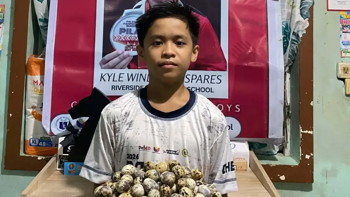 Twelve-year-old chess player Kyle Windylle C. Espares holds a tray of quail eggs in front of his Palarong Pambansa congratulatory poster as he fundraises for the 7th ASEAN+ Individual Chess Championships.