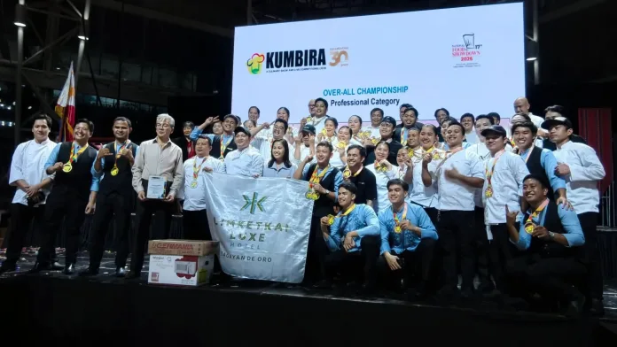 Chefs, staff, and management of Limketkai Luxe Hotel hold their banner, medals, and championship certificate on stage while celebrating as overall champions in the professional division of Kumbira 2026 at The Atrium of Limketkai Mall in Cagayan de Oro City.