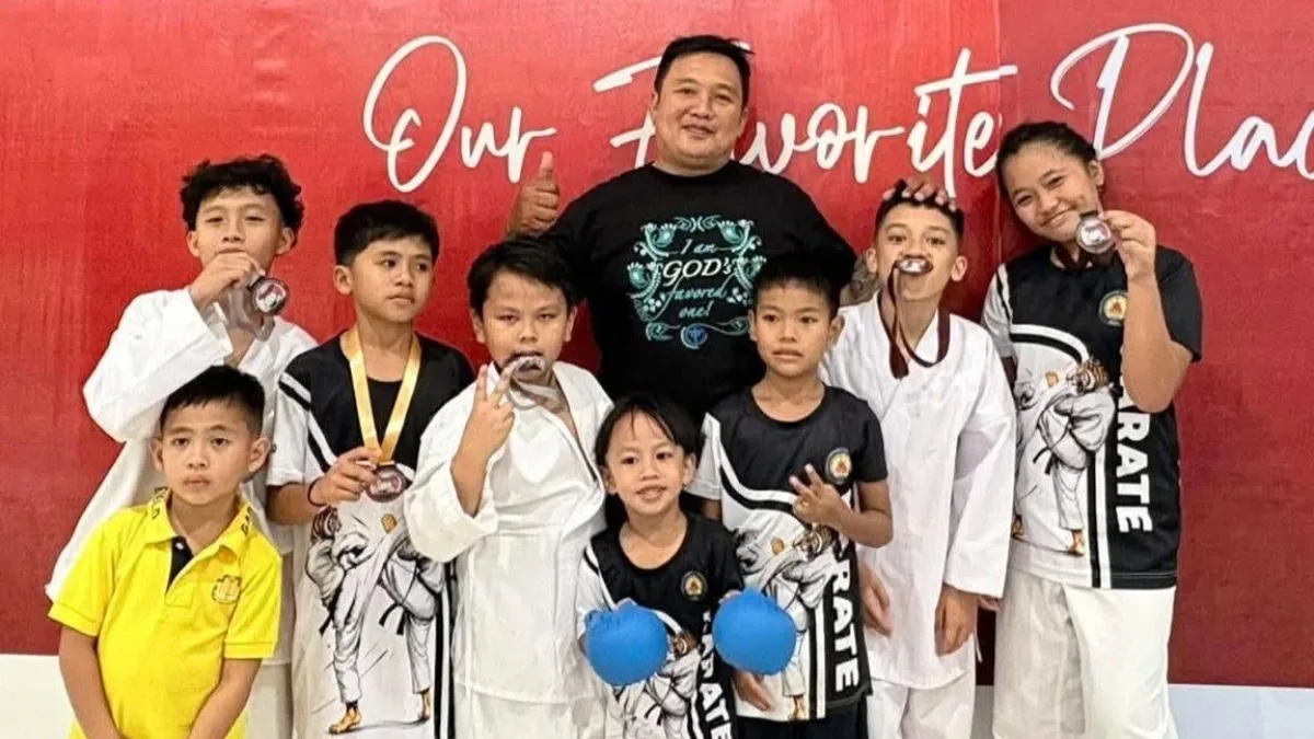 Head coach Jovanne Gabule poses with young novice karate athletes from Barangay Lumbia, Cagayan de Oro, as they display their medals inside Robinsons Valencia.