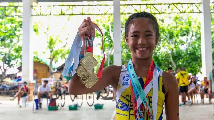 Nine-year-old triathlete Ma. Georjina Concepcion Pacquing Sumaje of Zamboanga City proudly holds up three gold medals after sweeping her events at the 2026 National Age Group Triathlon Camotes Island Series in Cebu.