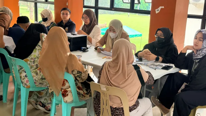 Marawi Compensation Board intake officers review documents and conduct validation procedures with local claimants across office tables in Marawi City, Lanao del Sur.