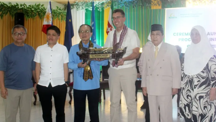 Marawi Compensation Board officials, led by Chairperson Maisara Dandamun-Latiph, present a traditional token to European Union Ambassador H.E. Massimo Santoro during the ceremonial launch of the Claims Processing Information System at Mindanao State University in Marawi City.