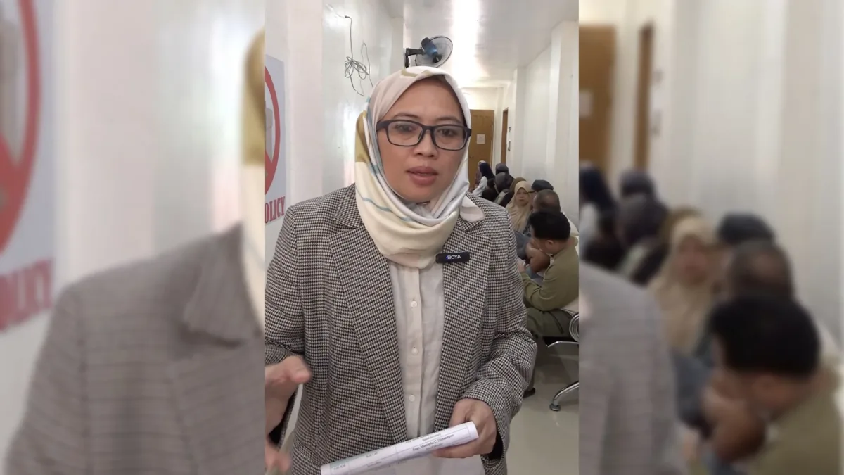 Marawi Compensation Board member Jamaica L. Dimaporo speaks while holding documentation in a hallway, explaining the digital Claims Processing Information System to claimants seeking compensation for the 2017 Marawi siege.