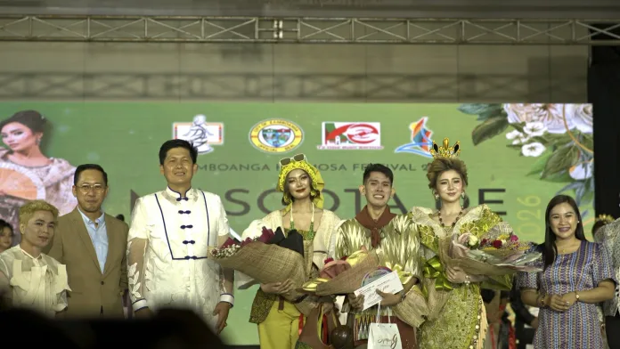 Winning designer Melvin Maverick Uyao holds his certificate and flowers on stage alongside models wearing Mascota de Zamboanga gowns, Zamboanga City Mayor Khymer Olaso, and city officials.