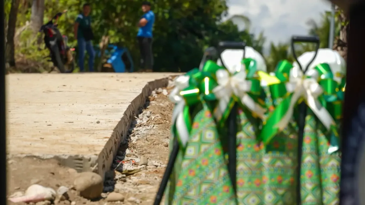 Ceremonial shovels decorated with green and white ribbons stand ready beside a newly paved road section during a groundbreaking event in Misamis Oriental.