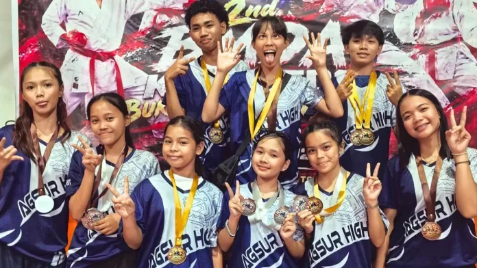 Young student-athletes of the MSUKC AGSURHIGH karatedo team from Agusan del Sur National High School smile and make hand gestures while presenting their tournament medals in Malaybalay City.
