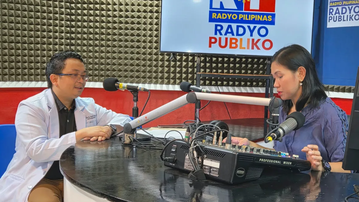 Northern Mindanao Medical Center psychiatrist Dr. Peter Santos wearing a white medical coat speaks into a studio microphone during a live broadcast on the Lambo Dyes radio program at Radyo Pilipinas in Cagayan de Oro City.
