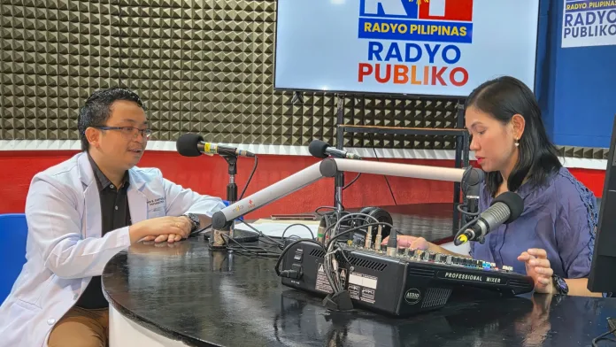 Northern Mindanao Medical Center psychiatrist Dr. Peter Santos wearing a white medical coat speaks into a studio microphone during a live broadcast on the Lambo Dyes radio program at Radyo Pilipinas in Cagayan de Oro City.