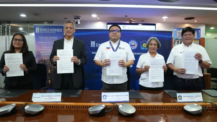 Five corporate and government executives stand side-by-side holding signed memorandum of understanding documents during the Pag-IBIG Fund and DMCI Homes strategic partnership ceremony.