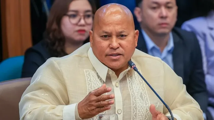 Senator Ronald "Bato" dela Rosa speaks into a microphone while wearing a traditional Barong Tagalog during a Senate committee hearing in Pasay City.